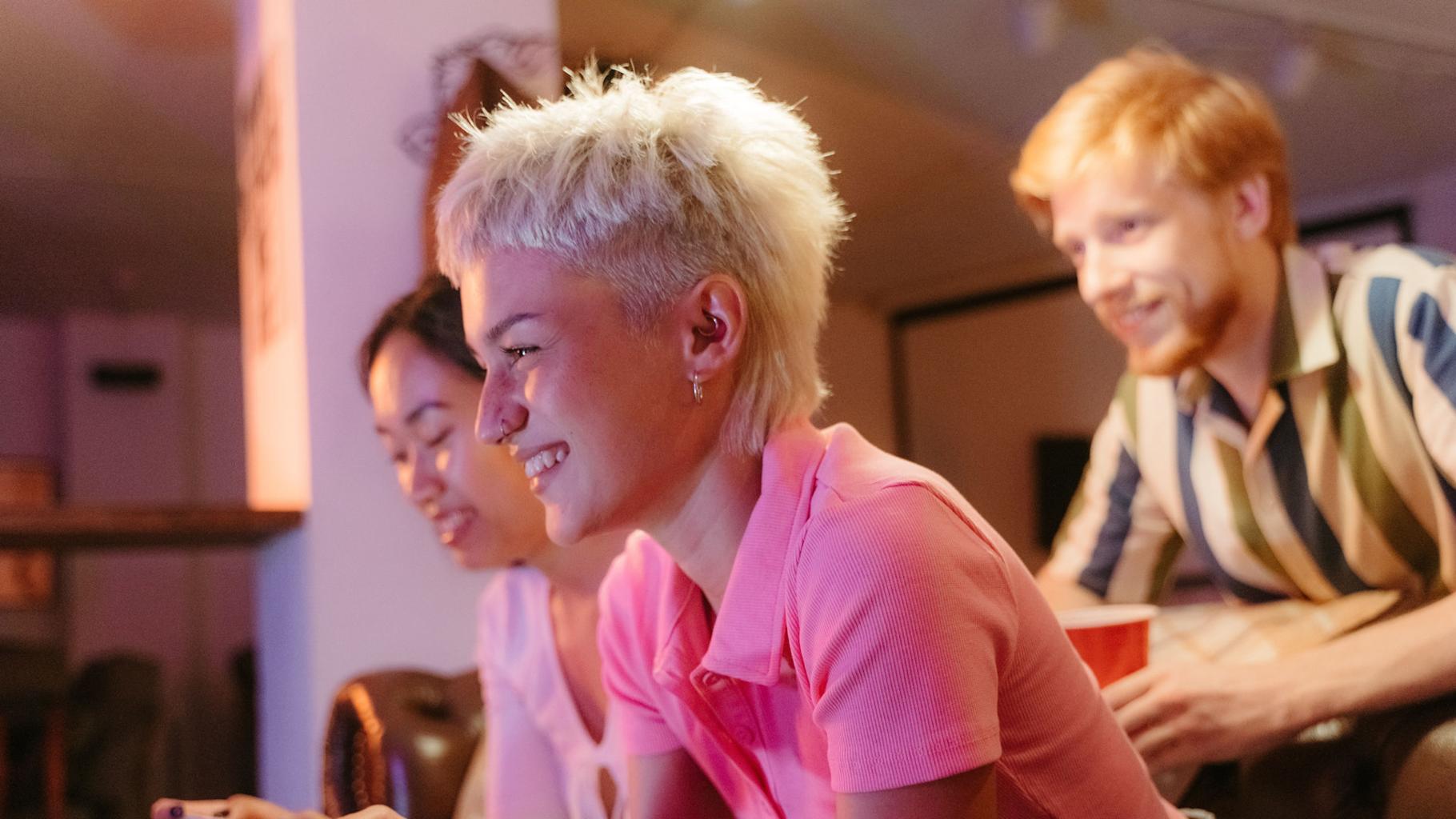 A group of people looking at the television and laughing. Credit: MART PRODUCTION via Pexels (https://www.pexels.com/photo/group-of-friends-playing-arcade-games-together-8885050/)