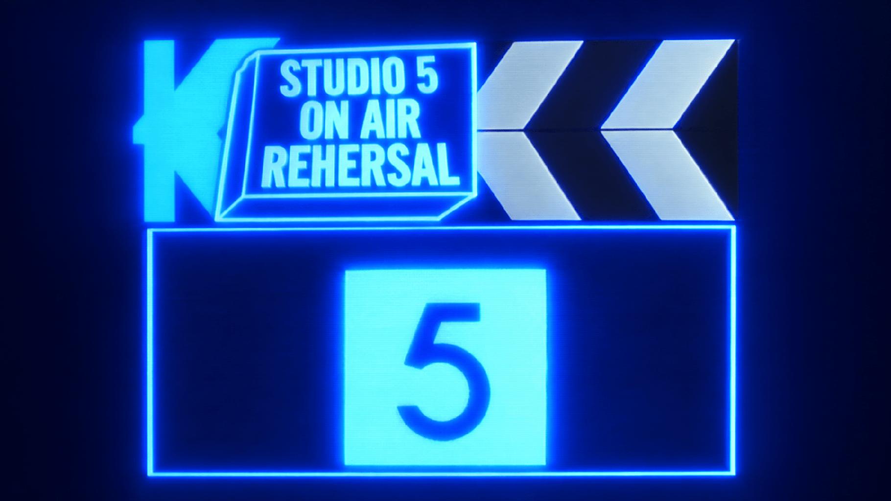 A screen from the opening sequence of Kellyvision, the 1988 TV show. It shows a clapperboard with an overlay that reads 'Studio 5 On Air Rehearsal'.