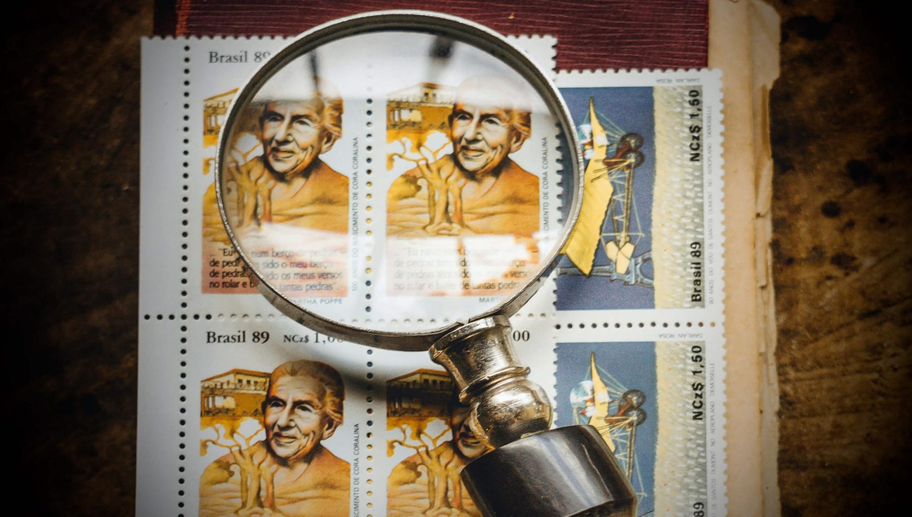 Magnifying glass with old vintage book and brazilian stamps. Photo by Koala on Unsplash.
